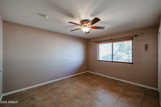 unfurnished room with ceiling fan and brick wall