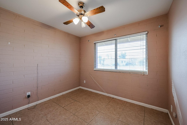 unfurnished room with ceiling fan and brick wall