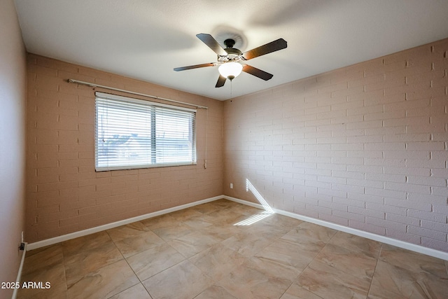 spare room with ceiling fan and brick wall