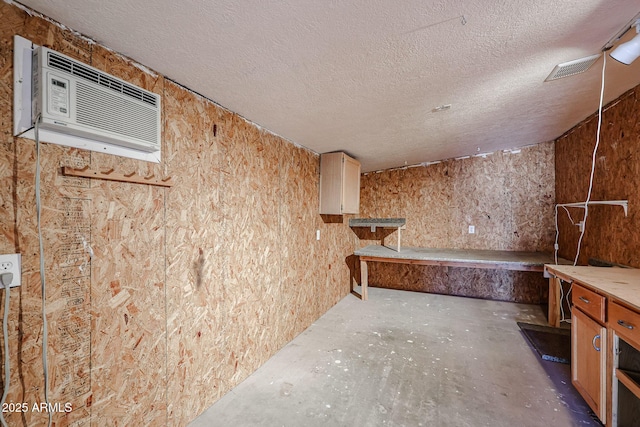 interior space featuring a wall mounted AC and a textured ceiling