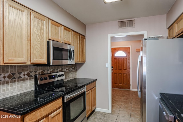 kitchen with tasteful backsplash, light tile patterned flooring, and appliances with stainless steel finishes