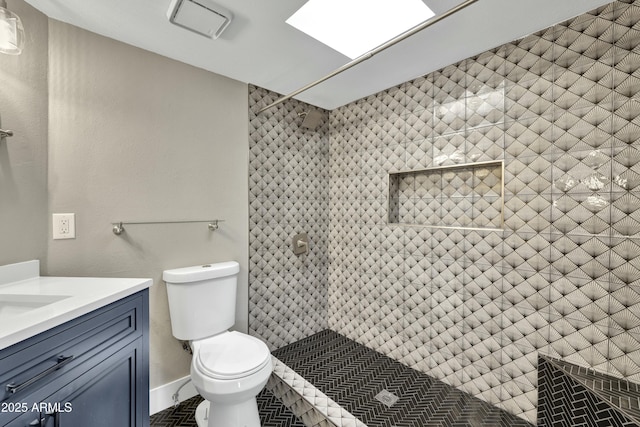 bathroom with toilet, vanity, and a tile shower