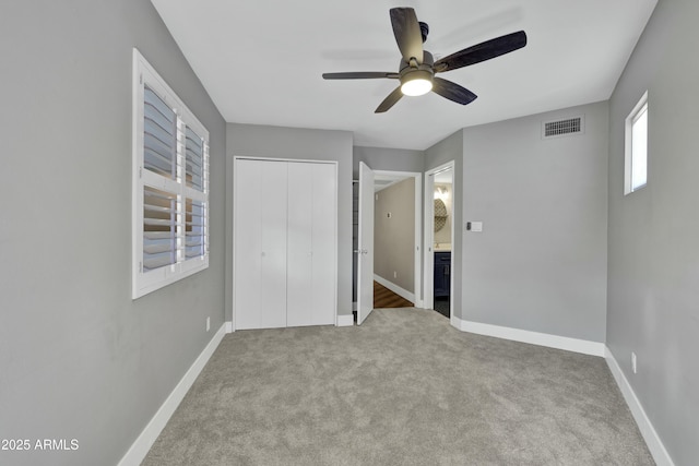 unfurnished bedroom featuring light carpet, ceiling fan, a closet, and connected bathroom