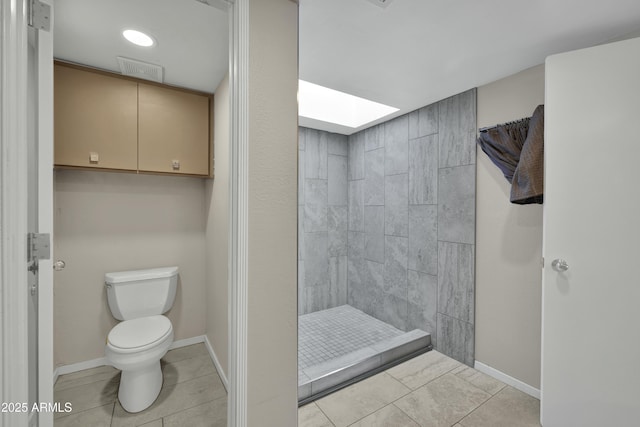 bathroom with toilet, a tile shower, and tile patterned floors