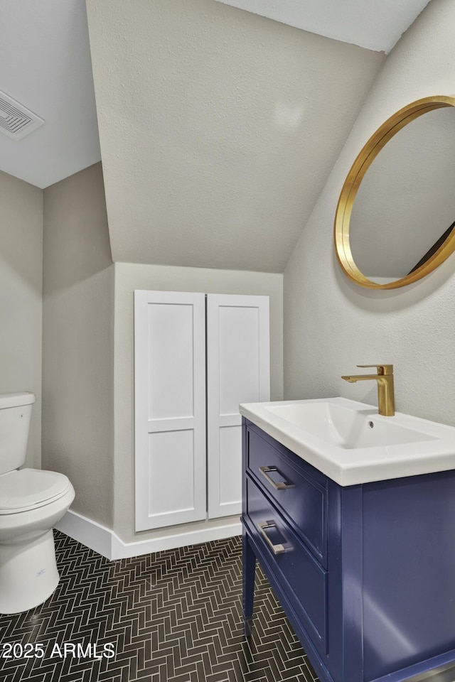 bathroom featuring toilet, vanity, lofted ceiling, and tile patterned flooring