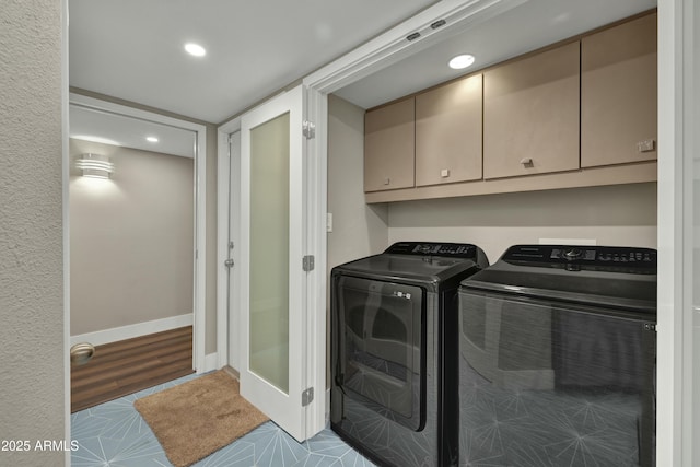 clothes washing area with washing machine and dryer, cabinets, and light tile patterned floors