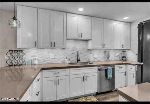 kitchen featuring white cabinets, black fridge, stainless steel dishwasher, pendant lighting, and sink