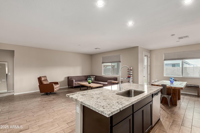 kitchen featuring visible vents, open floor plan, a sink, light stone countertops, and dishwasher