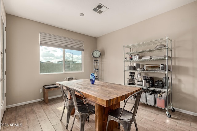 dining room with a toaster, baseboards, visible vents, and wood finish floors