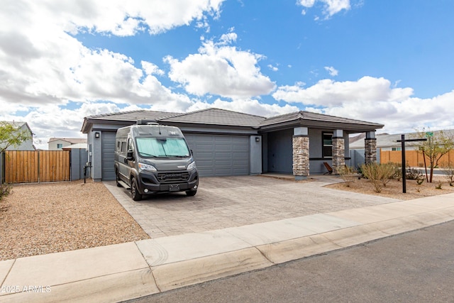 view of front facade with decorative driveway, a gate, fence, a garage, and a tiled roof