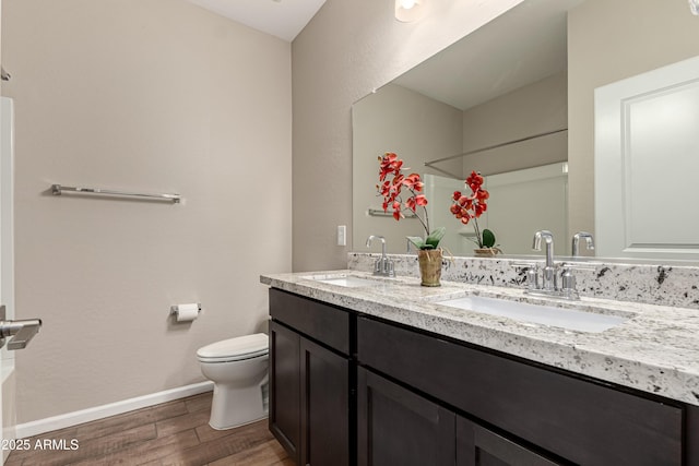 bathroom with toilet, baseboards, a sink, and wood finished floors