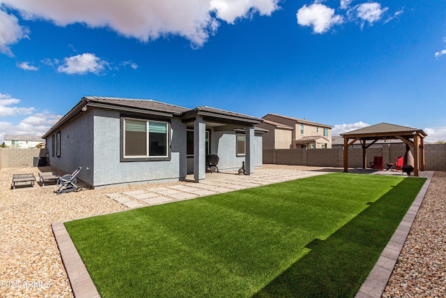 rear view of house featuring a yard, a patio, stucco siding, a gazebo, and a fenced backyard