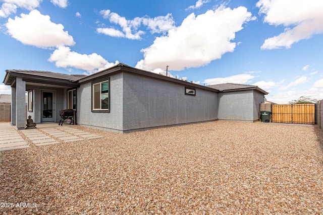 rear view of house with a gate, fence, a patio, and stucco siding