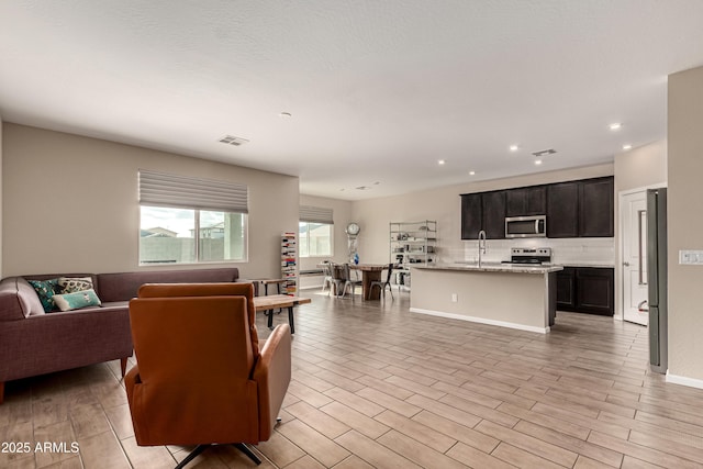 living area with wood tiled floor, visible vents, and recessed lighting