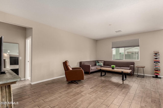 living room with baseboards, visible vents, and light wood finished floors