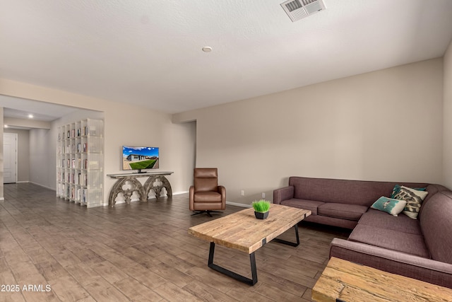 living area with baseboards, visible vents, and wood finished floors