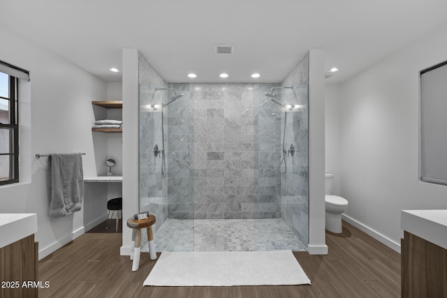 bathroom with vanity, wood-type flooring, toilet, and tiled shower