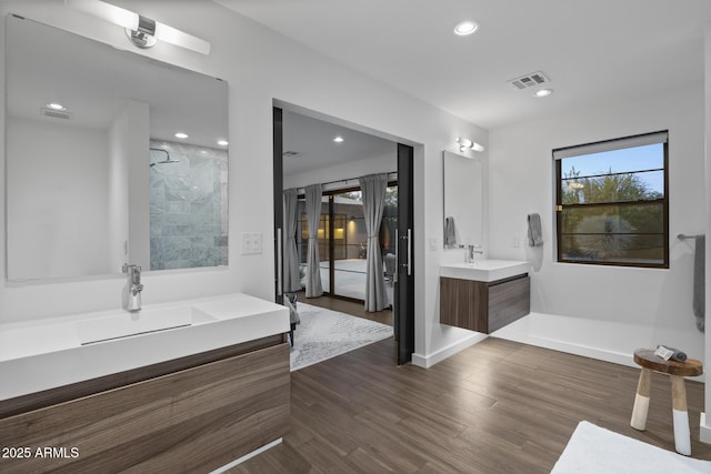 bathroom with hardwood / wood-style flooring, vanity, and a shower