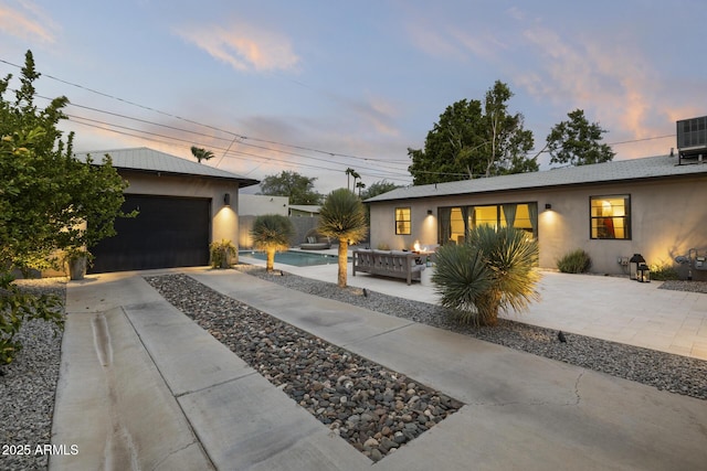 view of front of home with cooling unit, a garage, and an outdoor hangout area