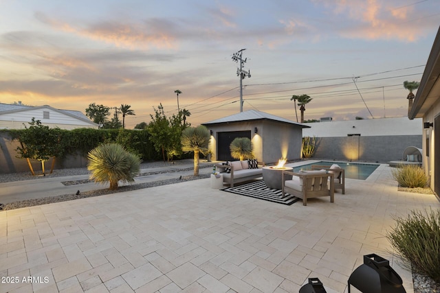 patio terrace at dusk featuring a fenced in pool, an outdoor structure, and a fire pit