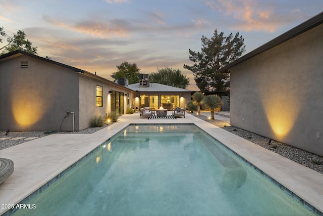 pool at dusk with a patio area