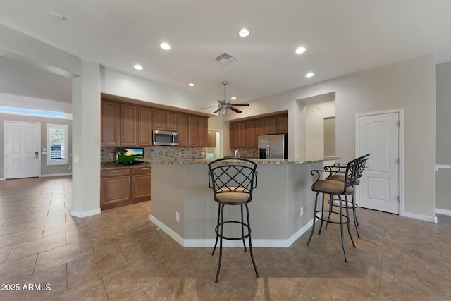 kitchen with appliances with stainless steel finishes, a breakfast bar, backsplash, and a large island