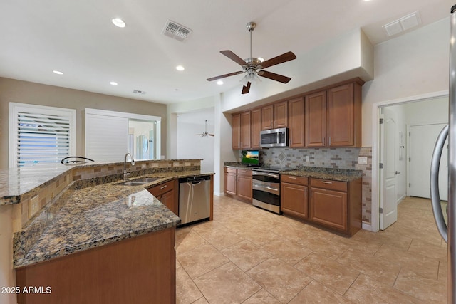 kitchen with tasteful backsplash, sink, dark stone counters, and appliances with stainless steel finishes