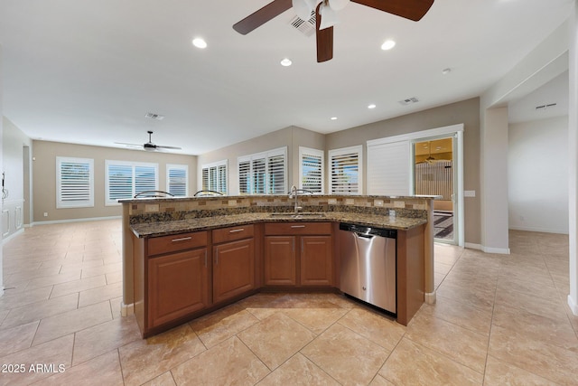 kitchen with sink, an island with sink, light tile patterned flooring, stainless steel dishwasher, and dark stone counters