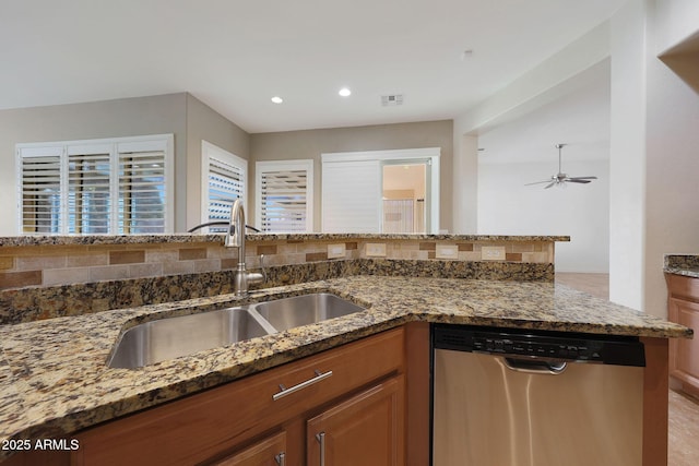 kitchen with sink, tasteful backsplash, stainless steel dishwasher, ceiling fan, and dark stone counters