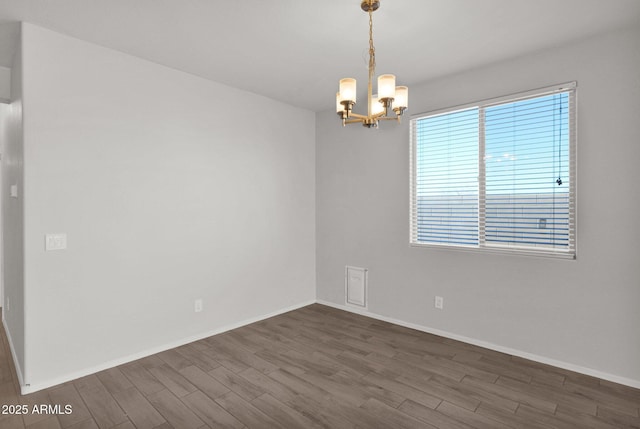 empty room featuring a notable chandelier and dark wood-type flooring