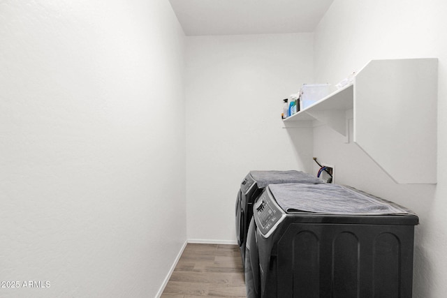 clothes washing area with separate washer and dryer and light wood-type flooring