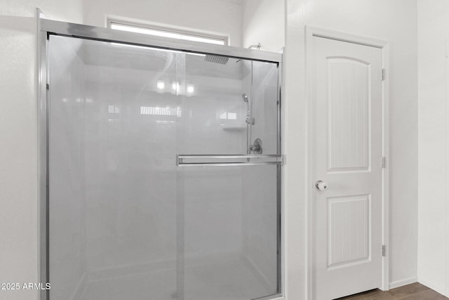 bathroom with wood-type flooring and a shower with shower door