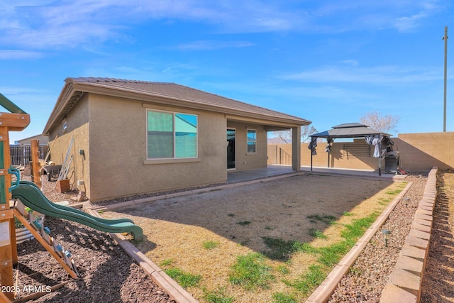 back of house featuring a gazebo and a playground