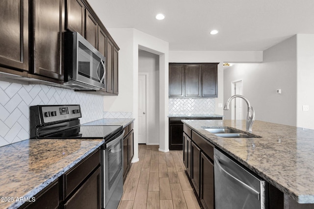 kitchen featuring appliances with stainless steel finishes, sink, light stone counters, and light wood-type flooring