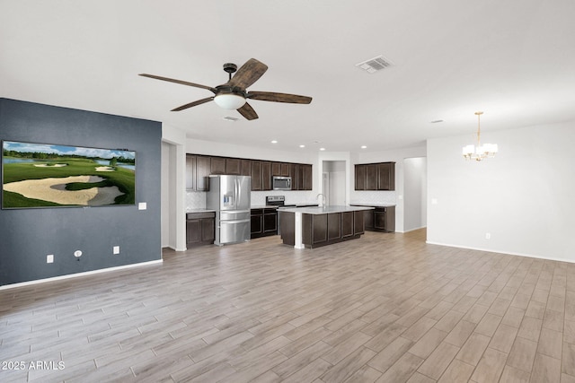 unfurnished living room with ceiling fan with notable chandelier and light wood-type flooring