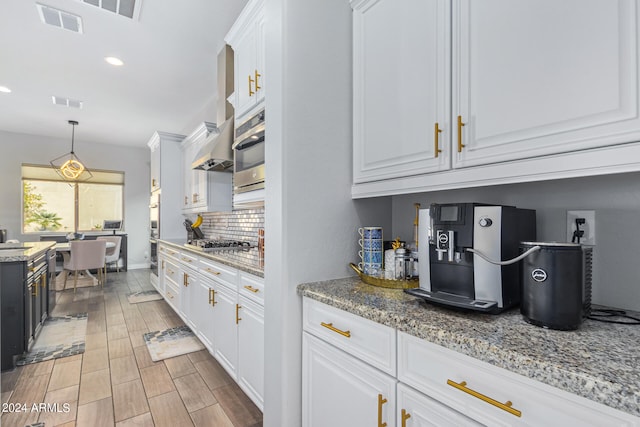 kitchen with pendant lighting, tasteful backsplash, white cabinets, and light stone counters