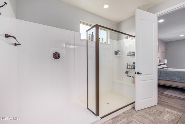 bathroom with a shower with door and tile flooring