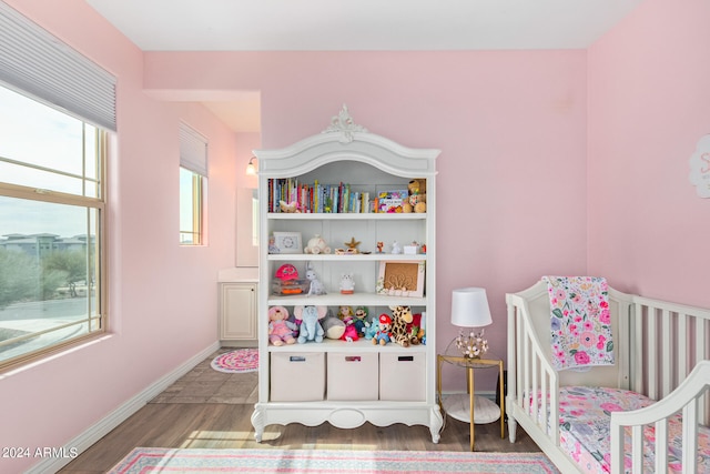 bedroom with a nursery area and dark wood-type flooring