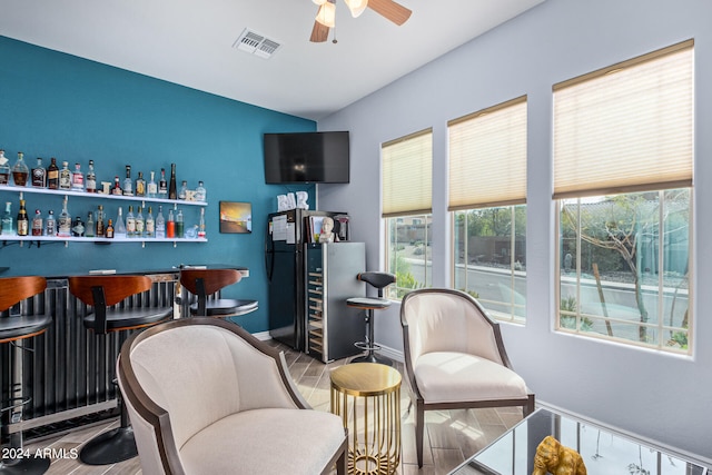 interior space featuring bar, wood-type flooring, and ceiling fan