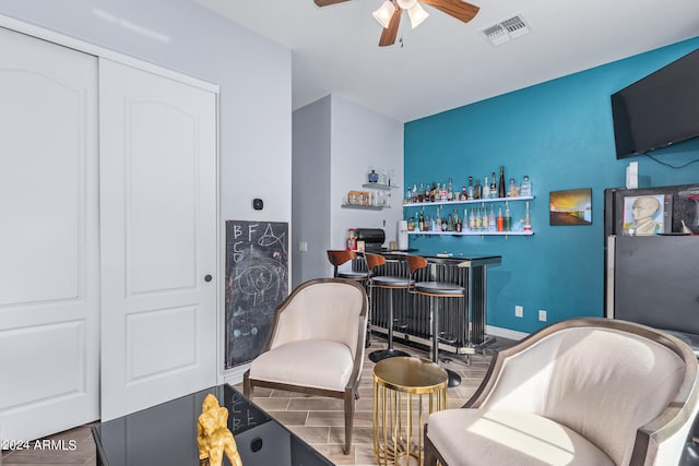 sitting room with ceiling fan, indoor bar, and dark hardwood / wood-style floors