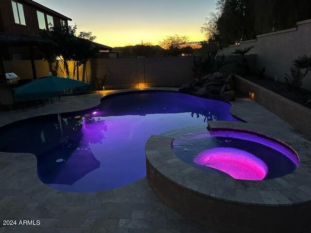 pool at dusk with an in ground hot tub