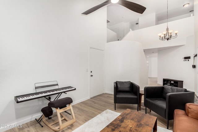 living room with ceiling fan, a high ceiling, and light wood-type flooring