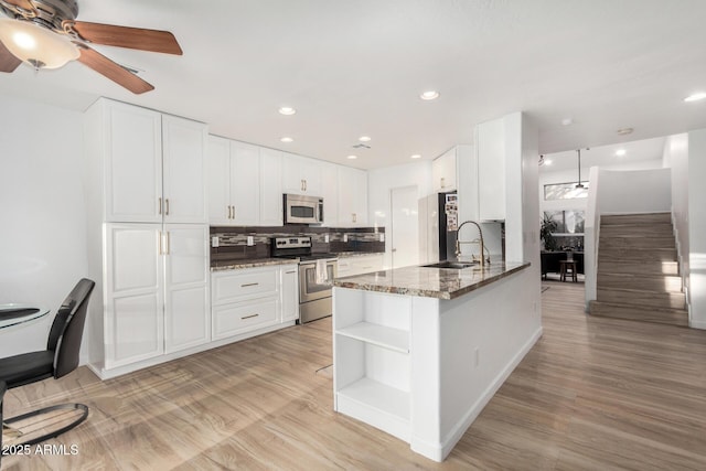 kitchen featuring dark stone countertops, stainless steel appliances, kitchen peninsula, and white cabinets