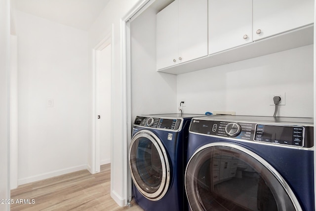 laundry area featuring cabinets, washer and dryer, and light wood-type flooring