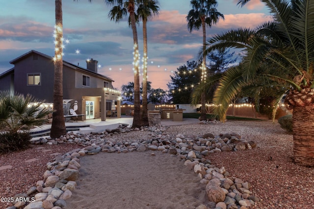 yard at dusk featuring a patio area and an outdoor kitchen