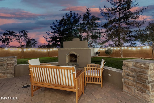 patio terrace at dusk featuring an outdoor living space with a fireplace