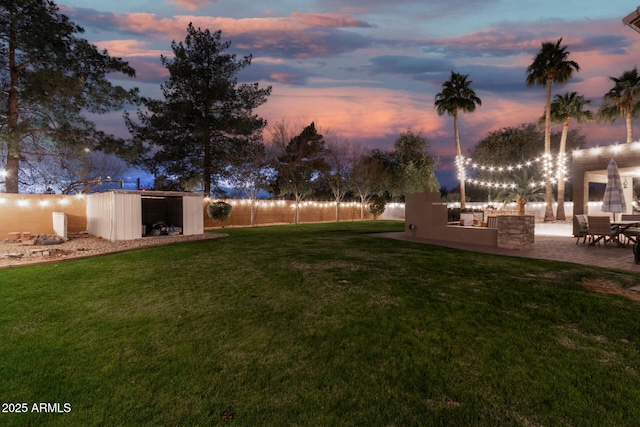 yard at dusk with an outdoor structure and a patio