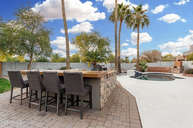 view of patio / terrace with exterior bar and a fenced in pool