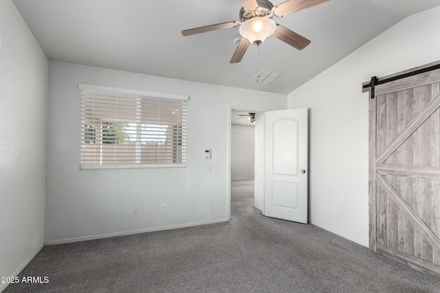 unfurnished bedroom with carpet, ceiling fan, a barn door, and vaulted ceiling