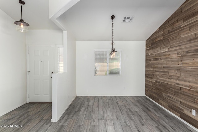 unfurnished dining area featuring dark hardwood / wood-style floors, lofted ceiling, and wood walls